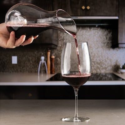 Red wine being poured from a glass decanter into a wine glass